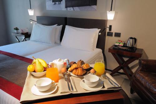 a breakfast tray with fruit and juice on a bed at iH Hotels Milano Ambasciatori in Milan