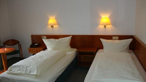 2 Betten in einem Zimmer mit 2 Lampen an der Wand in der Unterkunft Offenthaler Hof in Dreieich