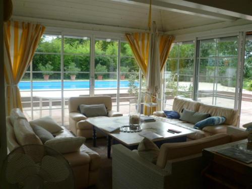 a living room with couches and a table and a pool at Bois Joli de la Freyère in Hindisheim