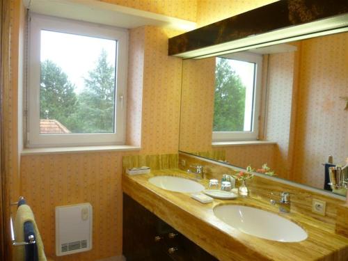 a bathroom with two sinks and a large mirror at Bois Joli de la Freyère in Hindisheim