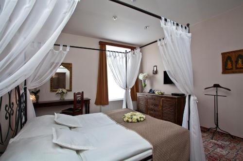 a bedroom with a white bed with white curtains at Hotel Tacl in Holešov