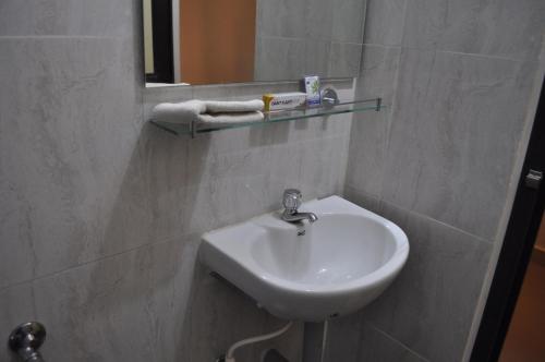 a bathroom with a white sink and a mirror at Jyothi Suites in Srīrangam