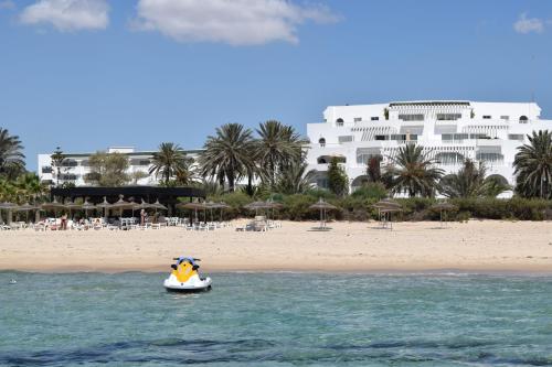 a small boat in the water in front of a beach at OCEANA Hotel & Spa in Hammamet