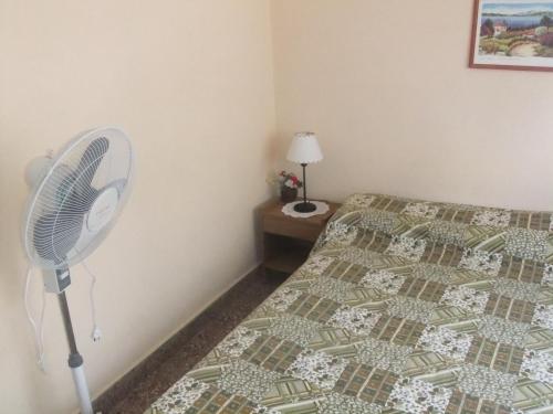 1 dormitorio con ventilador junto a una cama en Comodo Chalet en Gesell en Villa Gesell