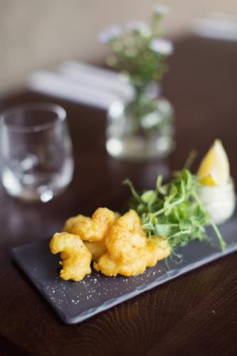 a black plate with food on a wooden table at The Inverkip Restaurant, Bar & Hotel in Inverkip
