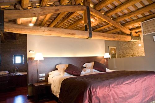 Un dormitorio con una cama grande en una habitación con techos de madera. en Mas Albereda, en Sant Juliá de Vilatorta
