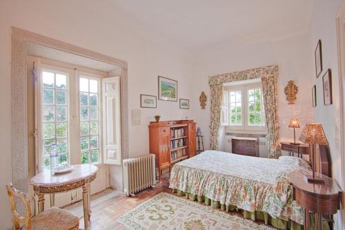 a bedroom with a bed and a desk and two windows at Quinta de Sao Thiago in Sintra