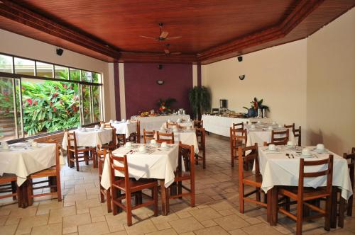 una sala da pranzo con tavoli bianchi e sedie in legno di Don Antonio Hotel a Ceres