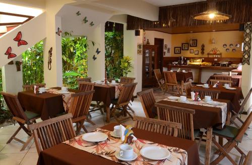 un restaurante con mesas, sillas y mariposas en la pared en Pousada Moryba, en Juquei
