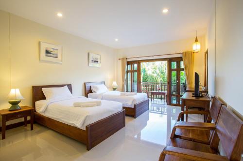 a bedroom with two beds and a balcony at Oh Amphawa Boutique Resort in Amphawa