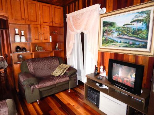 uma sala de estar com uma cadeira e uma televisão em Chale Bosque da Serra em Canela