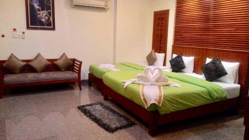 a bedroom with two beds and a couch at Busyarin Hotel in Nong Khai