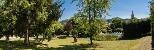a park with trees and a river and a church at Au Sans Souci in Saint-Paul-lès-Monestier