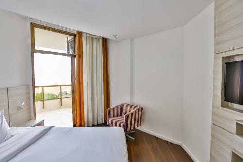 a bedroom with a bed and a tv and a chair at Hotel Orizzonte Niteroi by Atlantica in Niterói