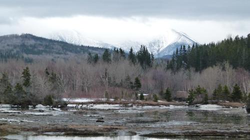 a snow covered mountain in the distance with a river at La Maison entre Mer Montagnes in Cap-Chat