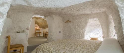 アルカラ・デル・フカルにあるCasa Cueva Las Tinajas de Nayaの白い部屋のベッドルーム1室(ベッド1台付)