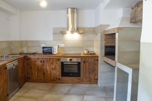 cocina con armarios de madera y microondas en Casa Cueva Las Tinajas de Naya en Alcalá del Júcar