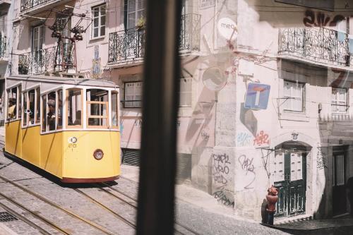 a yellow tram on a city street with graffiti at Santa Bica Eat Drink & Sleep in Lisbon