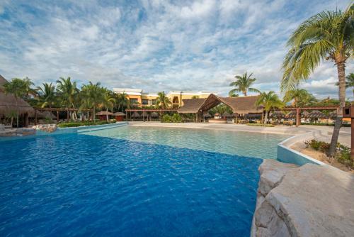 a swimming pool in a resort with palm trees at Iberostar Selection Paraíso Maya - All Inclusive in Puerto Morelos