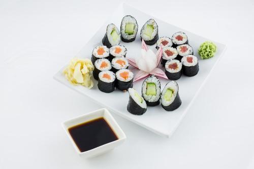 a plate of sushi on a white plate with soy sauce at Gasthaus Pavillon in Dresden