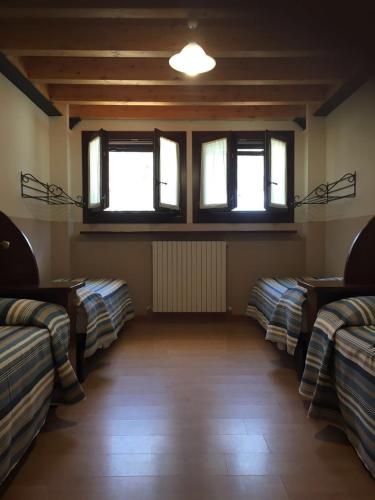 a room with three beds and two windows at Albergo Carpe Diem in Ligonchio