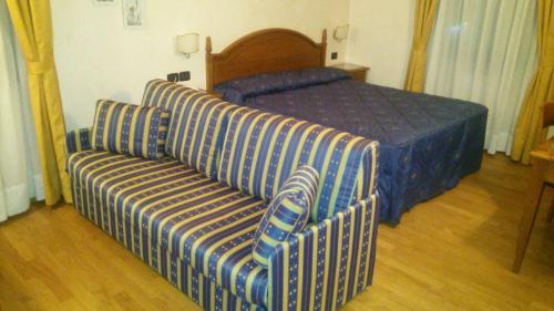 een slaapkamer met een bed, een bank en een stoel bij Albergo Carpe Diem in Ligonchio