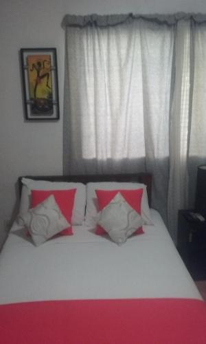 a bedroom with a bed with red and white pillows at Room in Cancun Stadium in Cancún