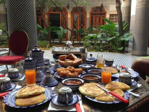 Riad Les Chrifis Navette Aéroport 24 sur 24 في فاس: طاولة مليئة بأطباق الطعام وعصير البرتقال
