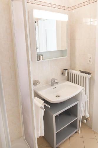 a white bathroom with a sink and a mirror at Il guscio in Cadro