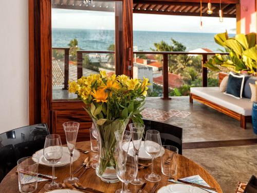 een tafel met glazen en een vaas met bloemen erop bij Castelo Pink Boutique Hotel in Uruau