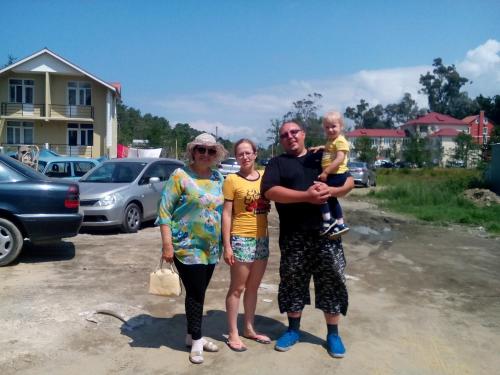 a family posing for a picture in a parking lot at Apartment Zhemchuzhina Ureki in Ureki