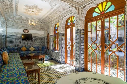 a living room with a blue couch and windows at Riad Les Chrifis Navette Aéroport 24 sur 24 in Fès