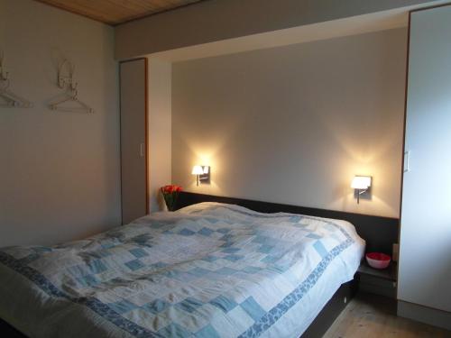a bedroom with a bed and two lights on the wall at Vigen ferielejligheder in Ebeltoft