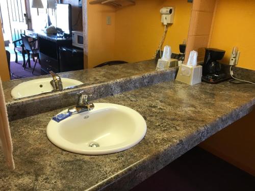 Pratt Budget Inn في Pratt: منضدة الحمام مع الحوض والمرآة