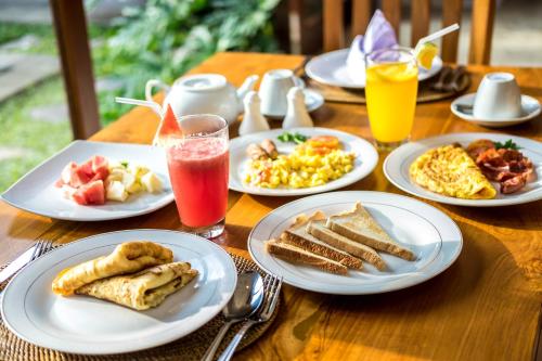 un tavolo in legno con piatti per la colazione e bevande di Naja Private Villa Ubud ad Ubud