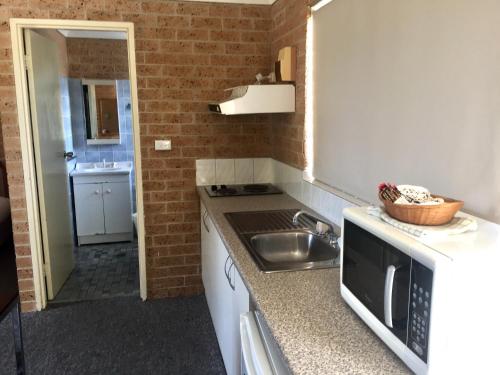 a small kitchen with a sink and a microwave at Huskisson Bayside Resort in Huskisson