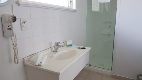 a white bathroom with a sink and a shower at Coachman Motel in Taihape