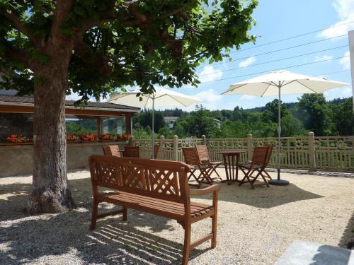 a wooden bench sitting next to a table and umbrella at Hôtel De La Plage in Le Chambon-sur-Lignon
