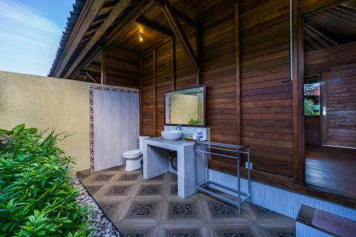 a bathroom with a sink and a toilet in a building at Laguna Reef Huts in Nusa Lembongan