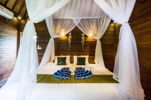 a bedroom with a bed with white drapes at Laguna Reef Huts in Nusa Lembongan
