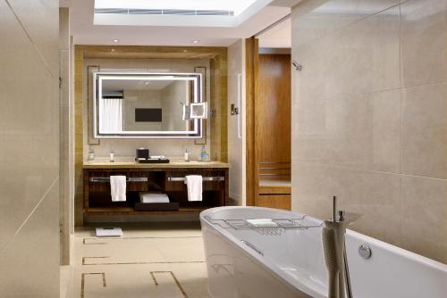 bagno con vasca, lavandino e specchio di The Royal Garden a Hong Kong