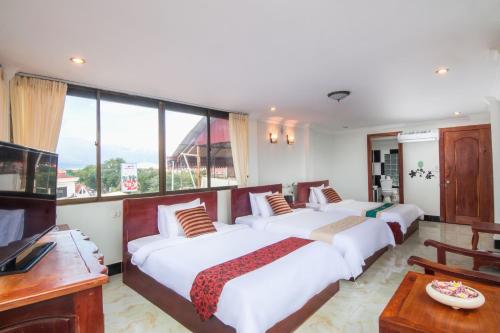 a bedroom with three beds and a large window at Angkor Udom Guesthouse in Siem Reap