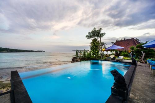 a swimming pool on the beach next to the water at Laguna Reef Huts in Nusa Lembongan