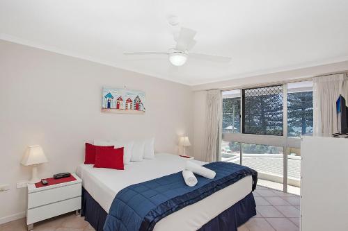 a white bedroom with a bed and a window at Solnamara Beachfront Apartments in Gold Coast