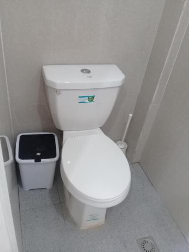a bathroom with a white toilet and a trash can at Sergi's Resort and Hotel in Palompon