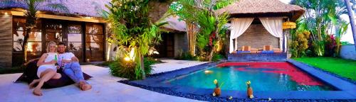 a man sitting next to a house with a swimming pool at The Zala Villa in Canggu
