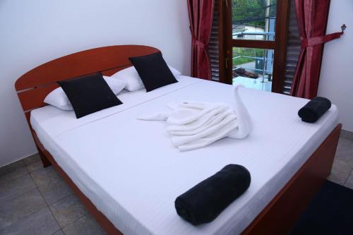 una cama con almohadas y guantes blancos y negros en White Horse Mirissa, en Mirissa