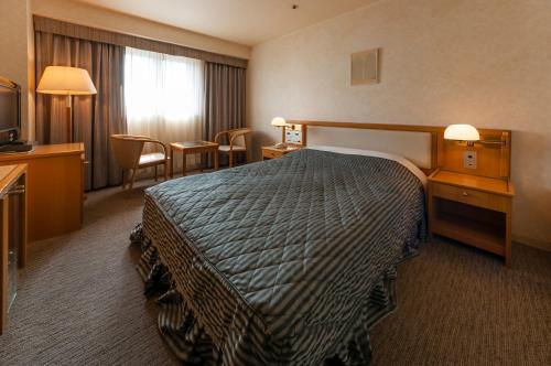Habitación de hotel con cama, mesa y sillas en Hotel Siena en Tokio