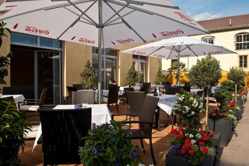 ein Restaurant mit Tischen und Sonnenschirmen auf einer Terrasse in der Unterkunft Am Schlosspark in Worms