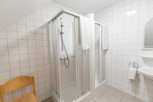 a white tiled bathroom with a shower and a sink at Gästehaus Ulrichsberg in Ulrichsberg